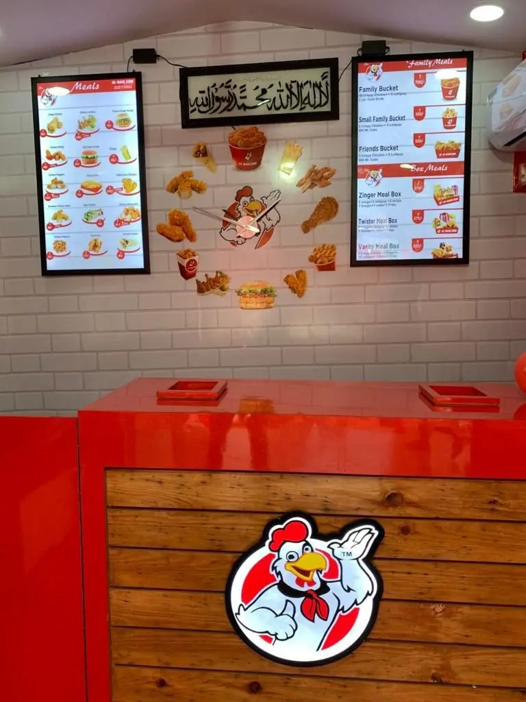 Counter and menu boards with family buckets and box meals inside AL-BAIK fried chicken restaurant, Bharuch, India