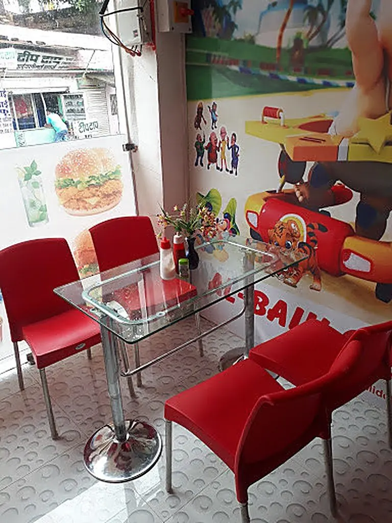 Dining area with a glass table and red chairs at AL-BAIK, Bharuch