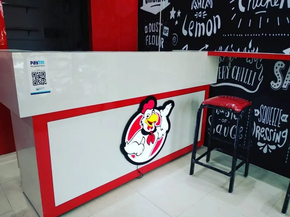 Order counter with the AL-BAIK chicken mascot and a payment QR code, Bharuch, India