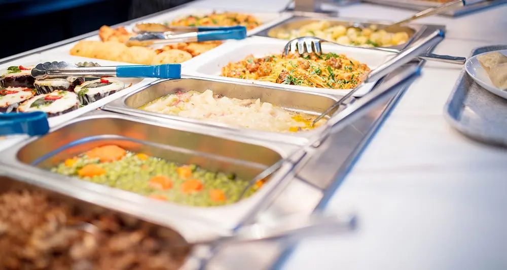Hot food counter with trays of vegetables, pasta and baked dishes, Geetha Hospitality catering